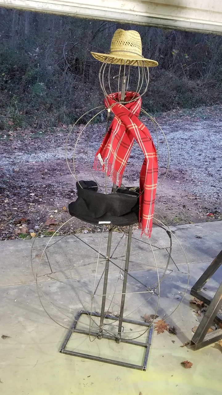 Hand-bent steel wire armature for the Frosty the Snowflake animatronic, with a straw hat and plaid scarf test-fitted