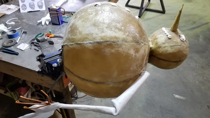 Tan fiberglass shell pieces for the Frosty animatronic on the studio workbench