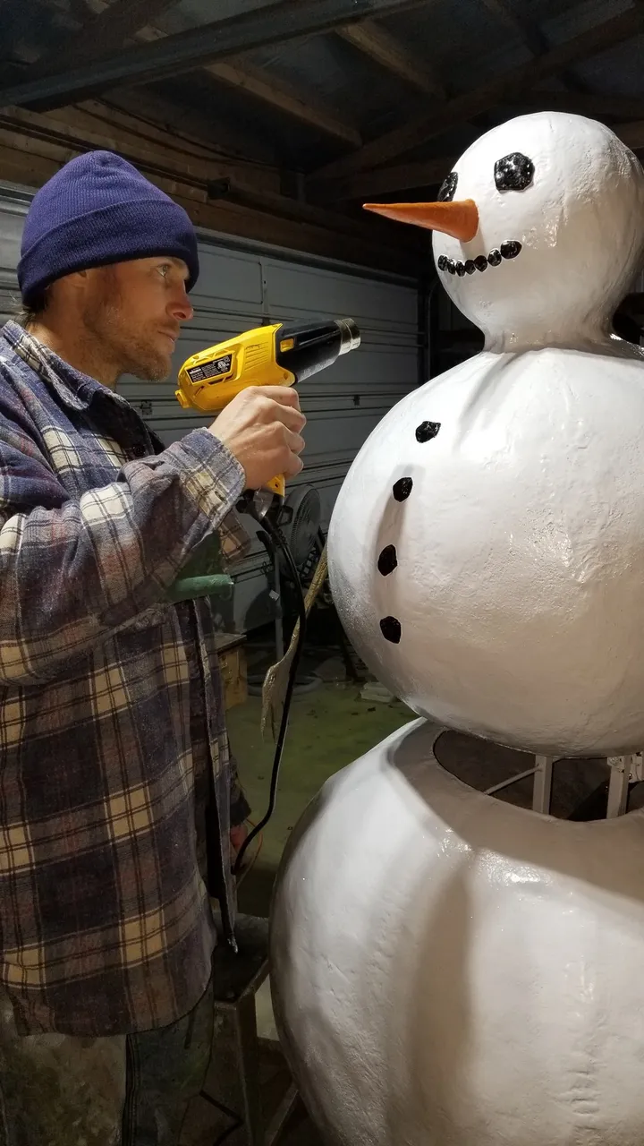 Dustin Weatherby heat-finishing the painted white Frosty the Snowflake animatronic with coal eyes and a carrot nose