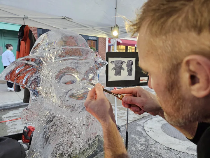 Dustin Weatherby detailing a clear ice sculpture of a character bust during a live carving performance