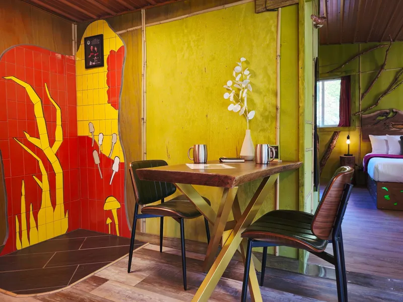 Live-edge dining table beside a hand-painted tile mural wall in the art bungalow