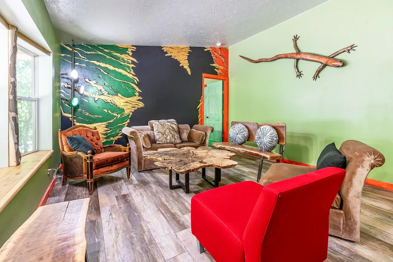 Styled living room with Dustin Weatherby's copper-finish wood salamander wall sculpture and gold-leaf mural