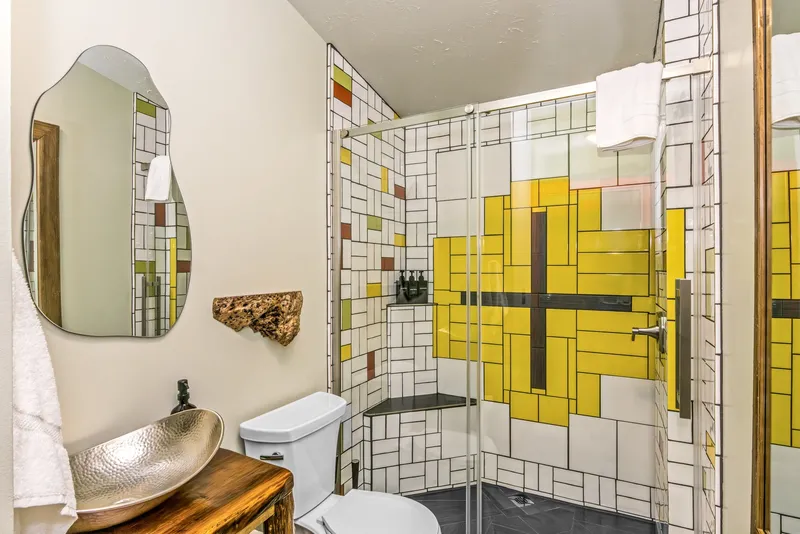 Bathroom with a geometric stained-glass-style tile mural and hammered copper vessel sink by Dustin Weatherby