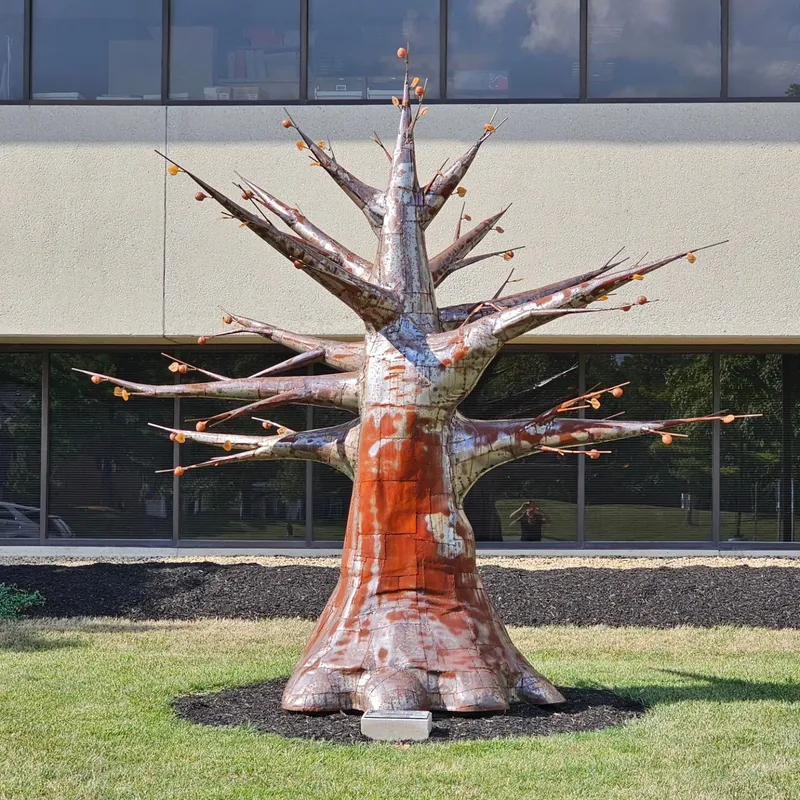 Large outdoor welded-metal tree sculpture installed at a civic building