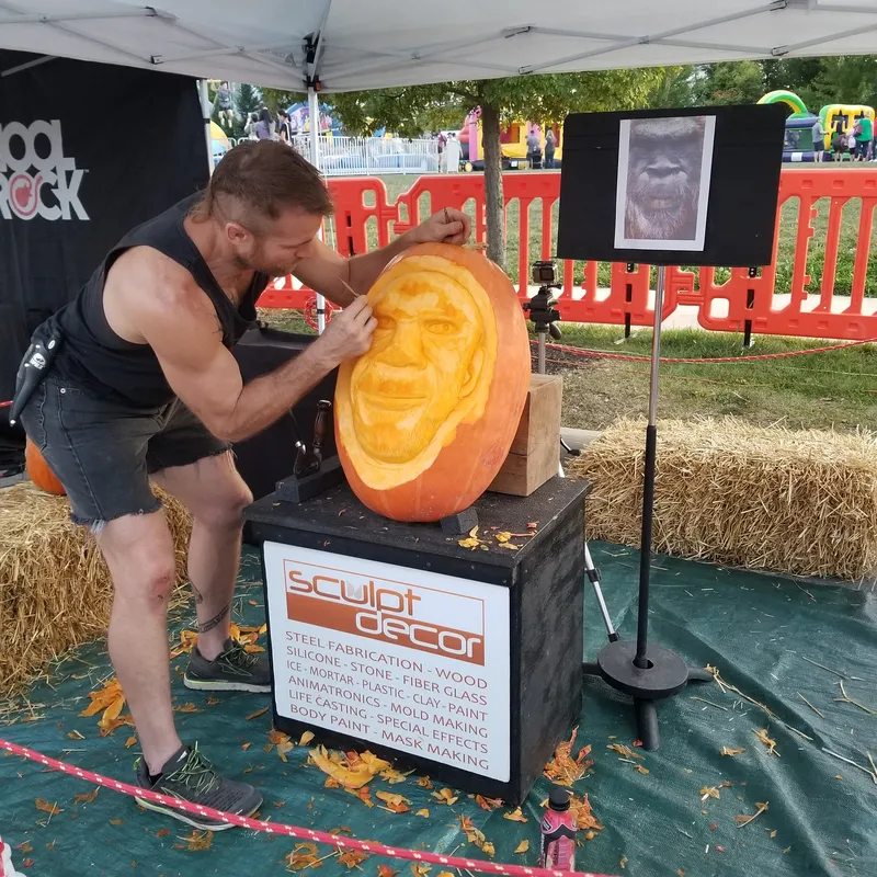 Dustin carving a Sasquatch face into a giant pumpkin at a festival