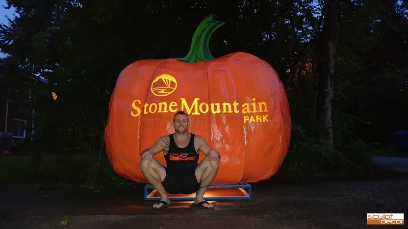 Dustin beside a giant Stone Mountain Park pumpkin he sculpted