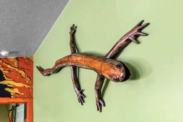 Carved wood salamander sculpture installed at Raven's Retreat Art Lodge
