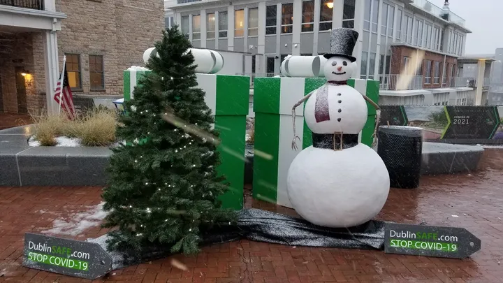 Frosty the Snowflake animatronic in a top hat and scarf, built by Dustin Weatherby for the City of Dublin, Ohio, beside a lit Christmas tree